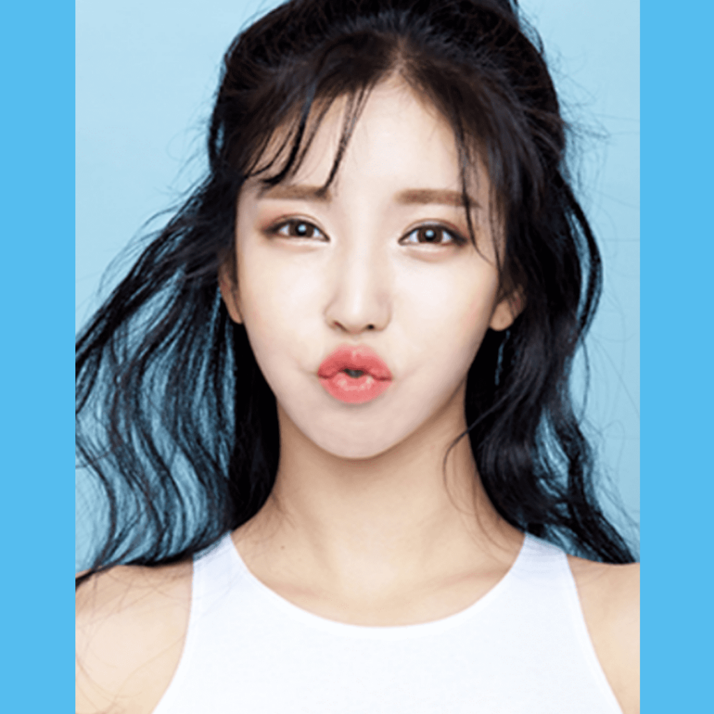Woman with long dark hair making a duck face expression against a light blue background